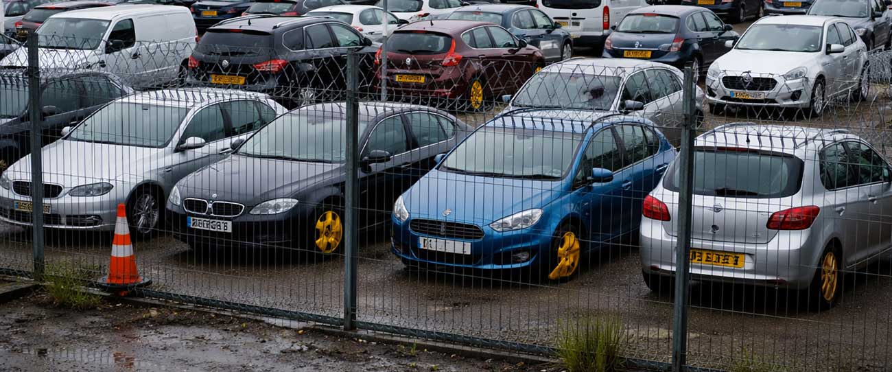 Cars behind fencing in an impound yard
